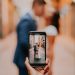 Hand holds phone in front of newly married couple