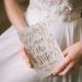 bride in white gown holding white and gold save the date for wedding