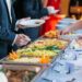 Bride and groom make their plates at self-service catered wedding buffet
