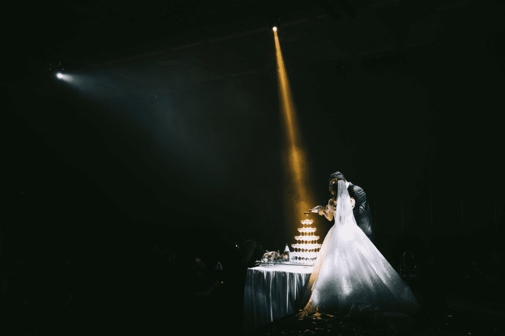 Bride and groom pour champagne under spotlight