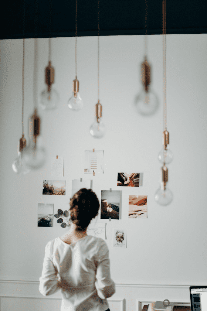 Woman stands in front of vision board taped to her wall.