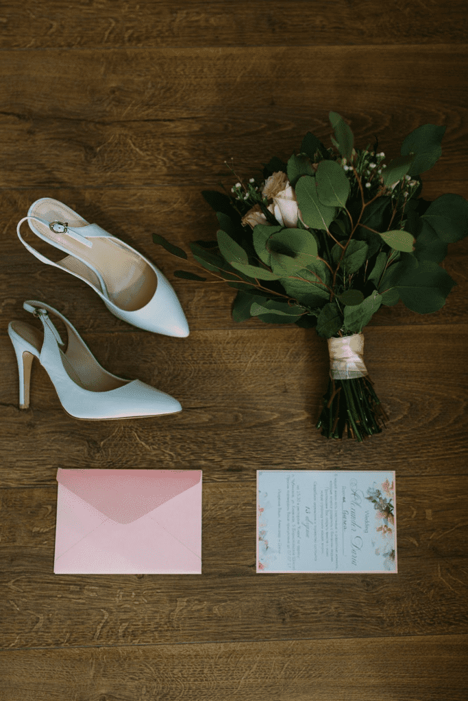 Flat lay image of bridal shoes, bouquet and wedding invitation. 