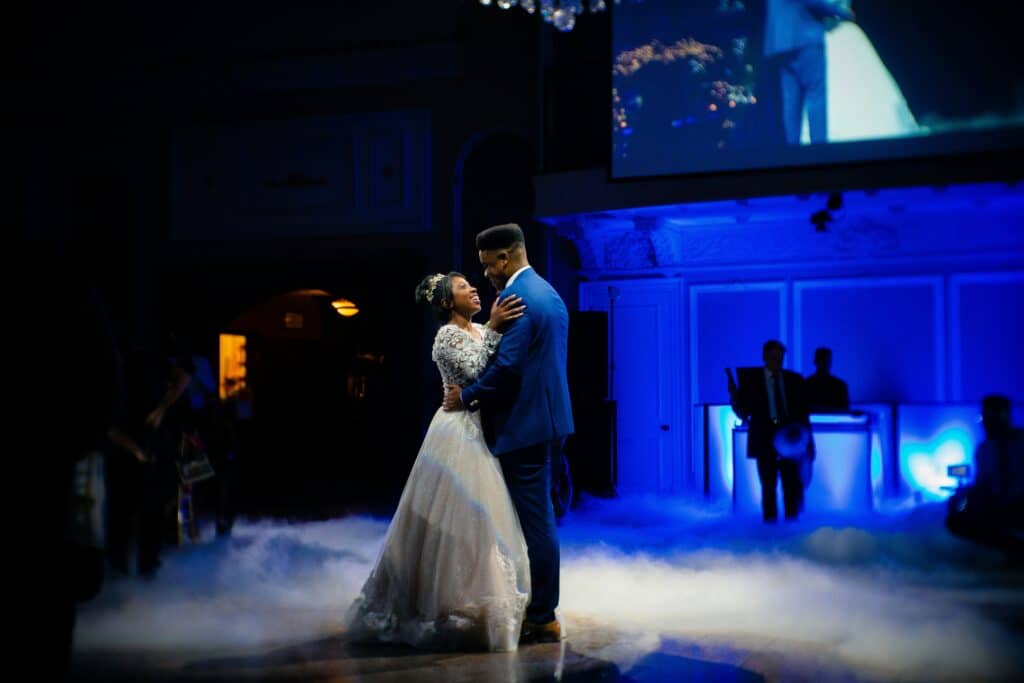Couple dancing on wedding dancefloor with spotlight and dramatic LED blue lighting.
